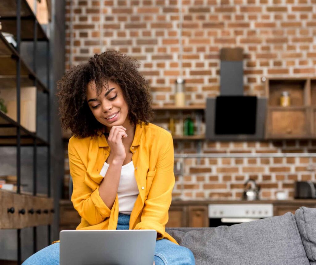 Uśmiechnięta dziewczyna siedzi w mieszkaniu przed komputerem