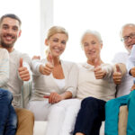 Uśmiechnięci rodzice, dzieci i dziadkowie siedzą na kanpie