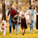 Mama i tata z dziecmi i psem biegną w parku