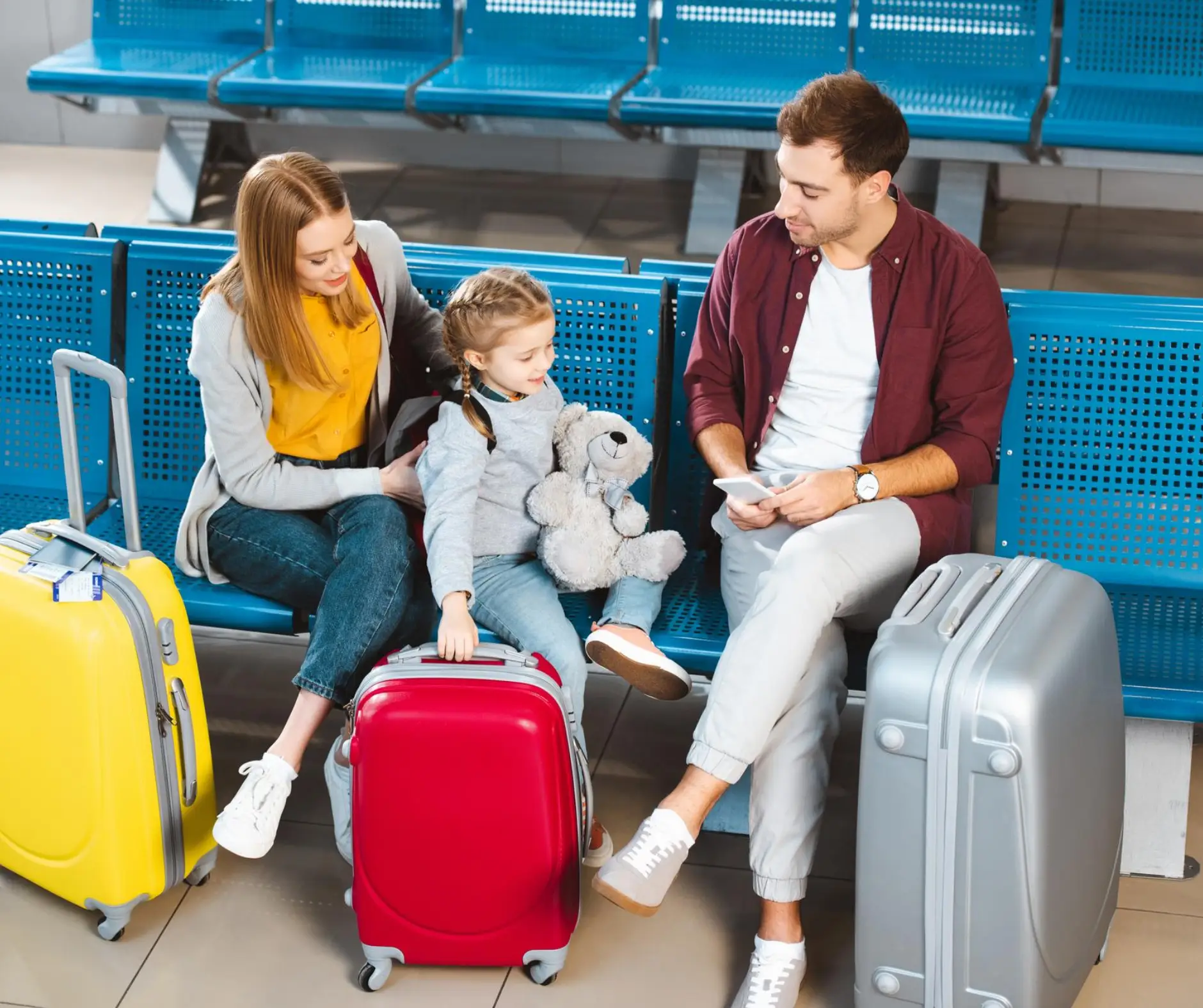 mężczyzna, kobieta i dziecko siedzą w poczekalni na ławce z bagażem